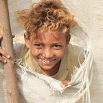 طفل يمني نازح يبتسم من خيمة ممزقة